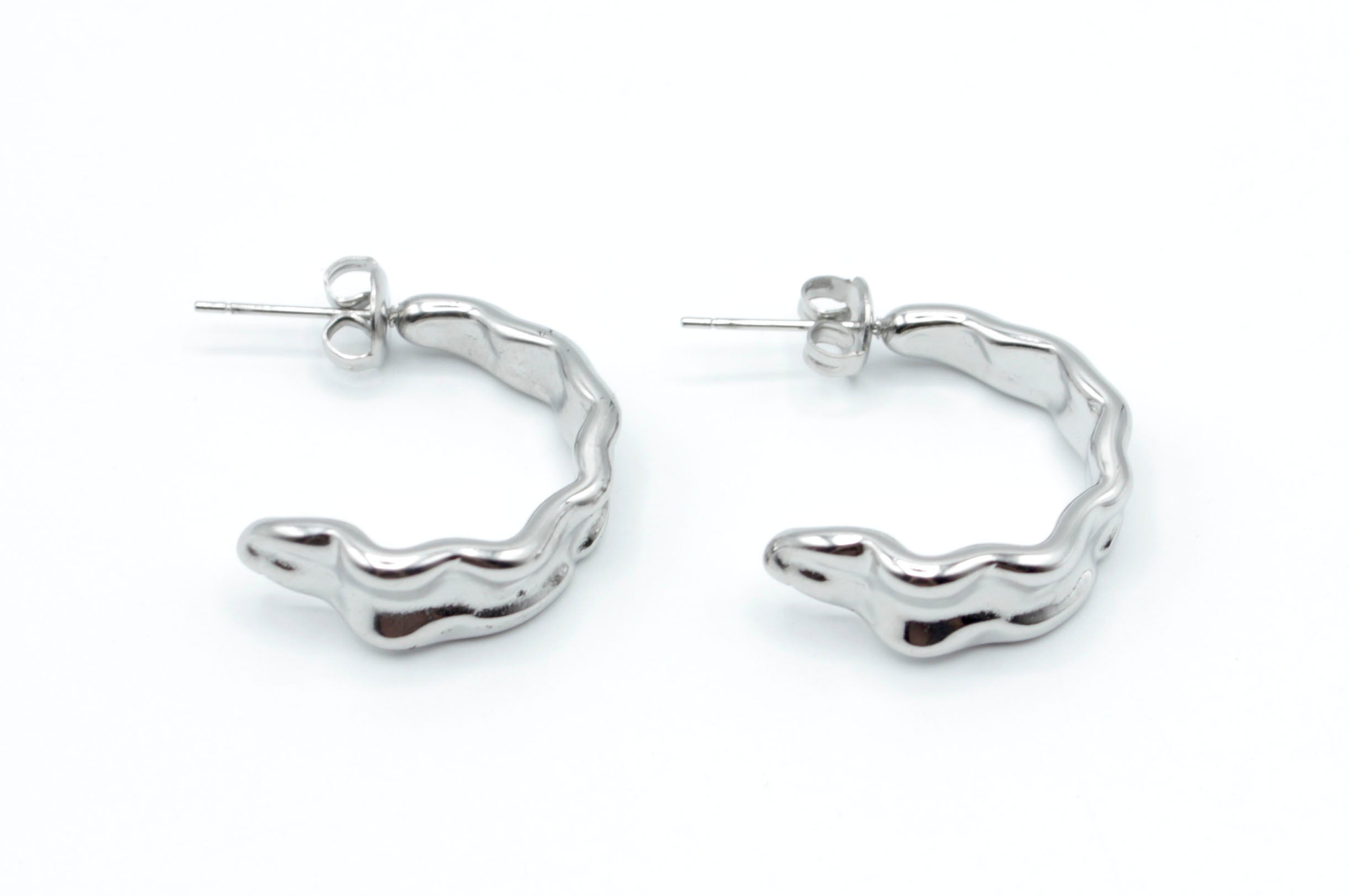 Pendientes Celeste de aro abierto plateado en acero inoxidable hipoalergénico y resistente al agua, con diseño ondulado moderno y cierre mariposa.