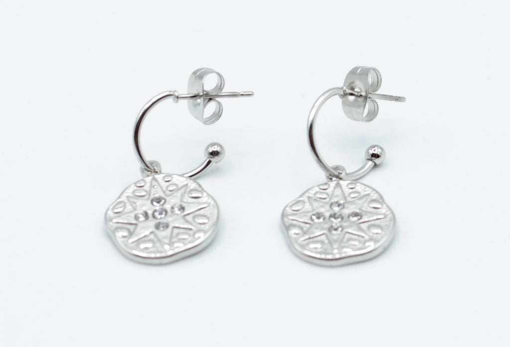 Aros Polar plateados en acero inoxidable hipoalergénico, resistentes al agua, con charm redondo decorado con estrella y cierre de presión mariposa