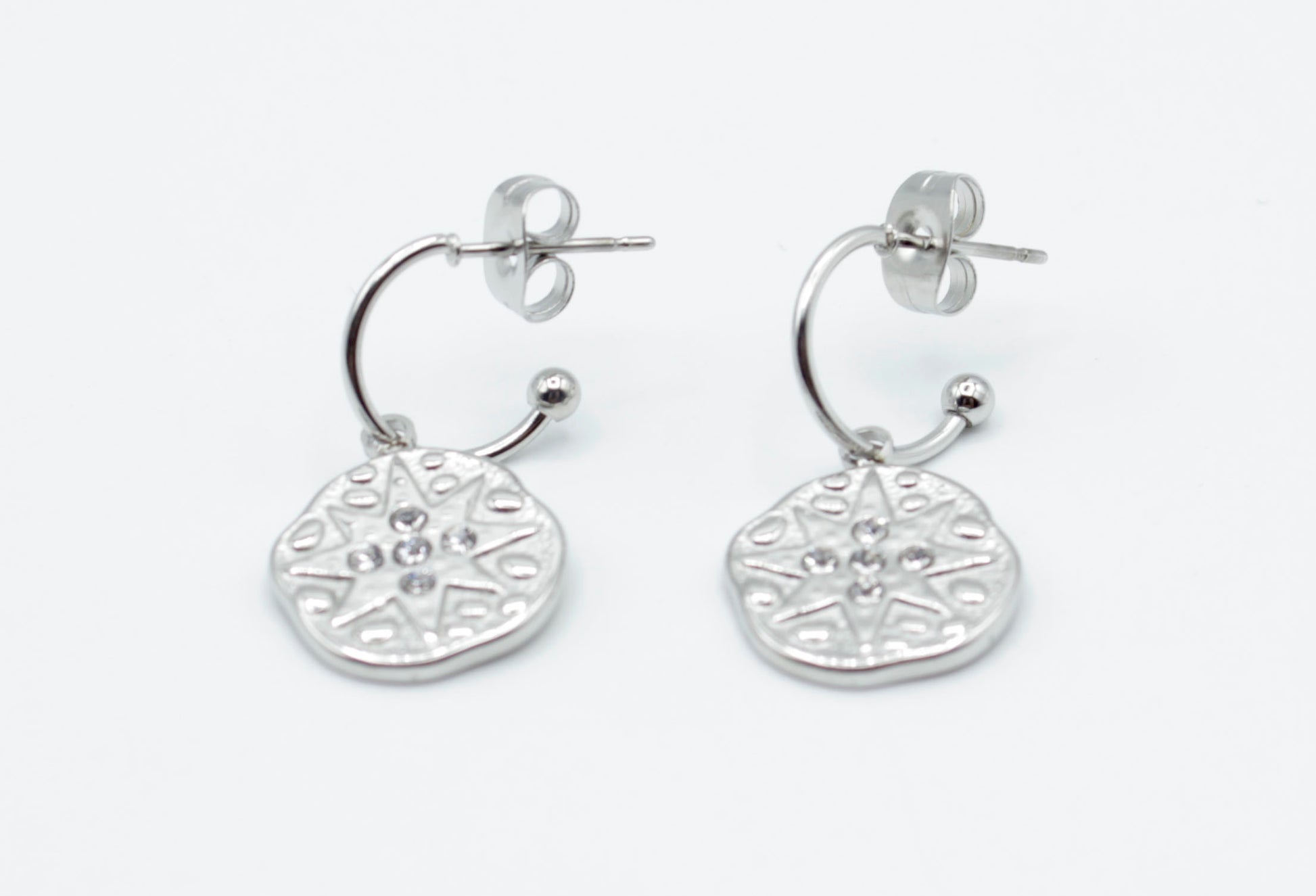 Aros Polar plateados en acero inoxidable hipoalergénico, resistentes al agua, con charm redondo decorado con estrella y cierre de presión mariposa