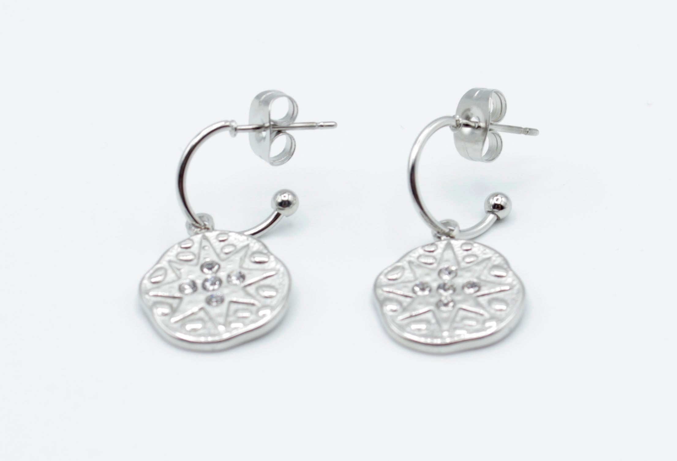Aros Polar plateados en acero inoxidable hipoalergénico, resistentes al agua, con charm redondo decorado con estrella y cierre de presión mariposa