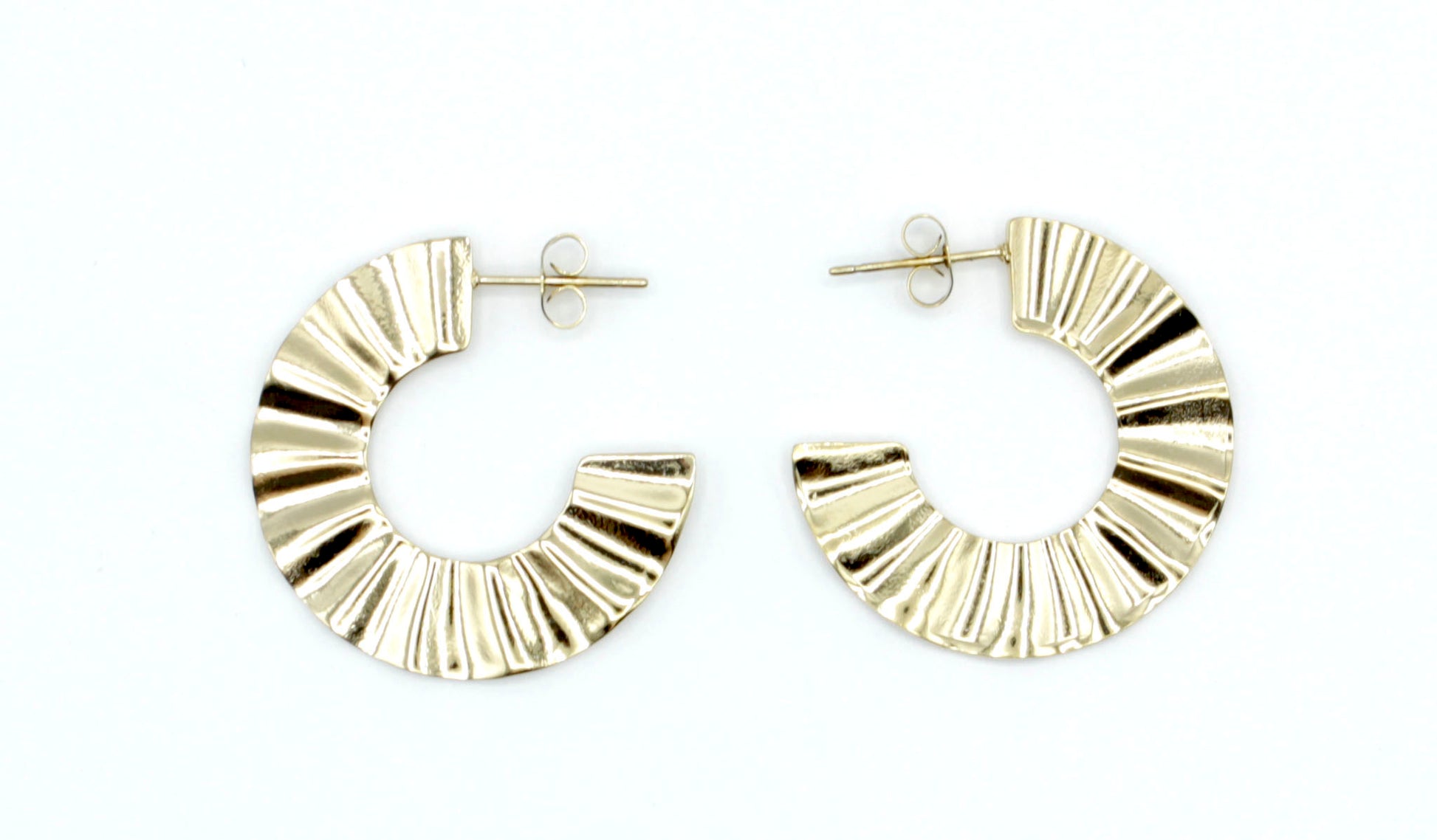 Pendientes de aro Sur en color dorado con relieve plisado, fabricados en acero inoxidable hipoalergénico, resistentes al agua y muy duraderos. Cierre de presión. DELACABRA