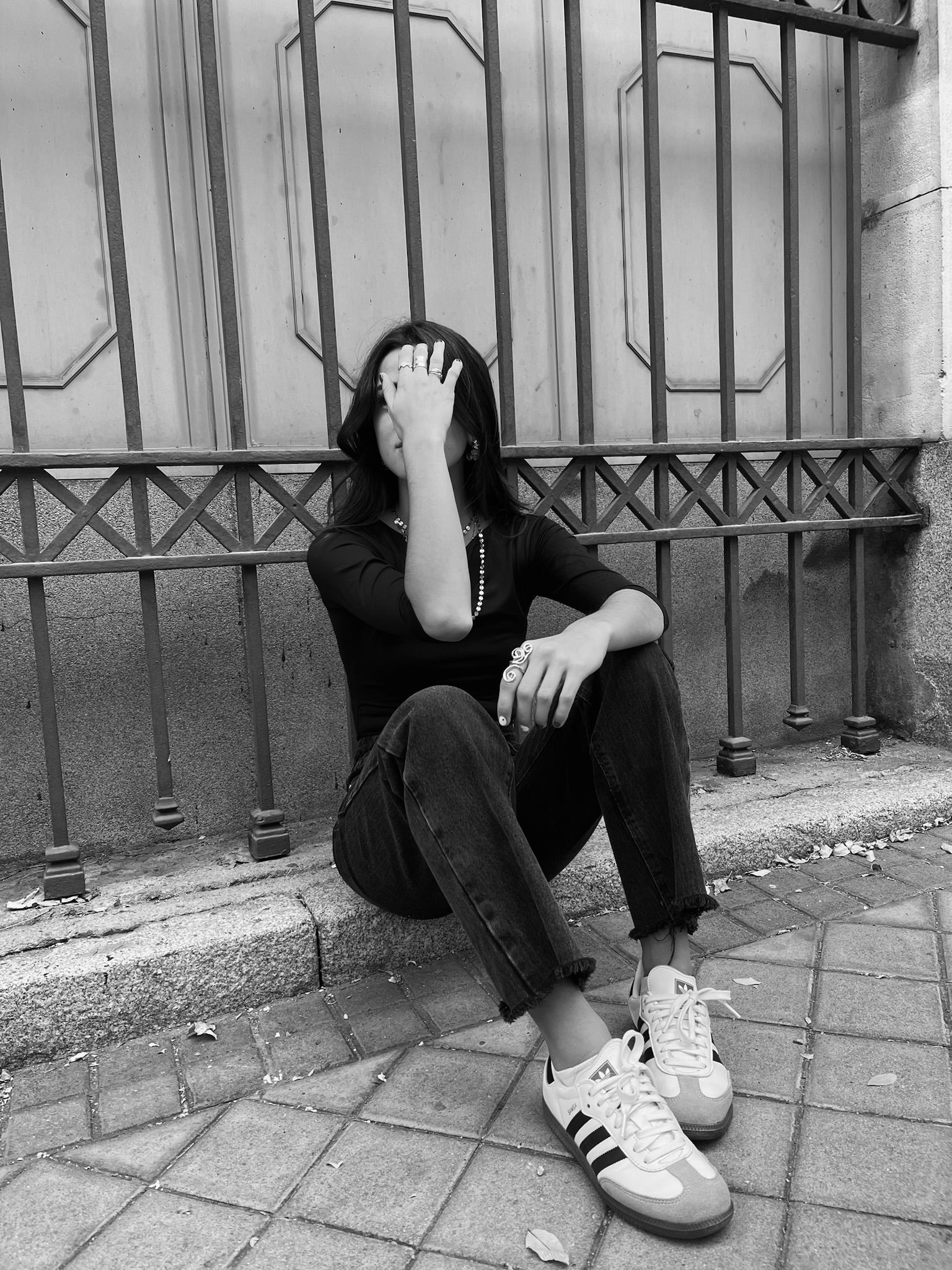 Foto en blanco y negro de una chica sentada en una acera con joyas DELACABRA.