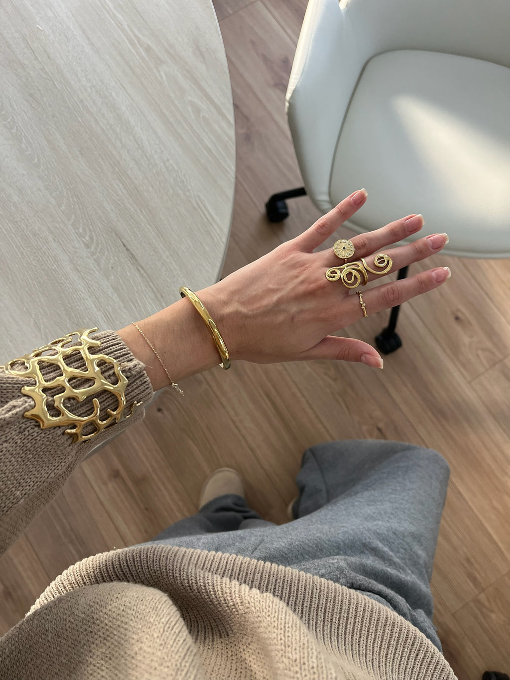 Brazalete diseño coral calado en acabado dorado puesto en la muñeca, combinado con anillos, hipoalergénico, resistente al agua, ajustable y duradero -DELACABRA