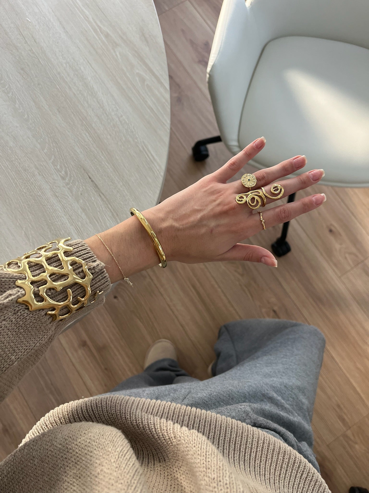 Brazalete diseño coral calado en acabado dorado puesto en la muñeca, combinado con anillos, hipoalergénico, resistente al agua, ajustable y duradero -DELACABRA