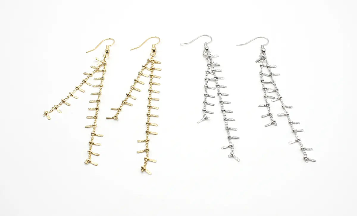 Pendientes largos de flecos en acero inoxidable, colores dorado y plateado, fondo blanco.