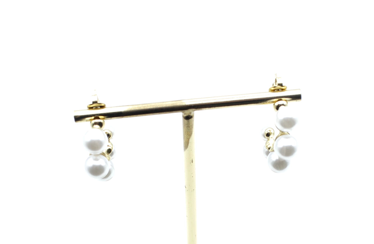 Aros Pearly dorados decorados con perlas blancas, acero inoxidable hipoalergénico y resistente al agua, presentados en expositor.