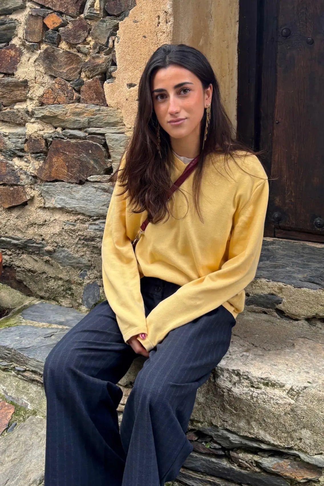 Mujer con estilo casual luce pendientes Henar dorados de acero inoxidable, largos con colgantes de conchas, hipoalergénicos, resistentes al agua y duraderos - DELACABRA