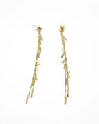 Pendientes largos Skyline dorados con finas cadenas y barritas colgantes. Acero amable con la piel de DELACABRA.