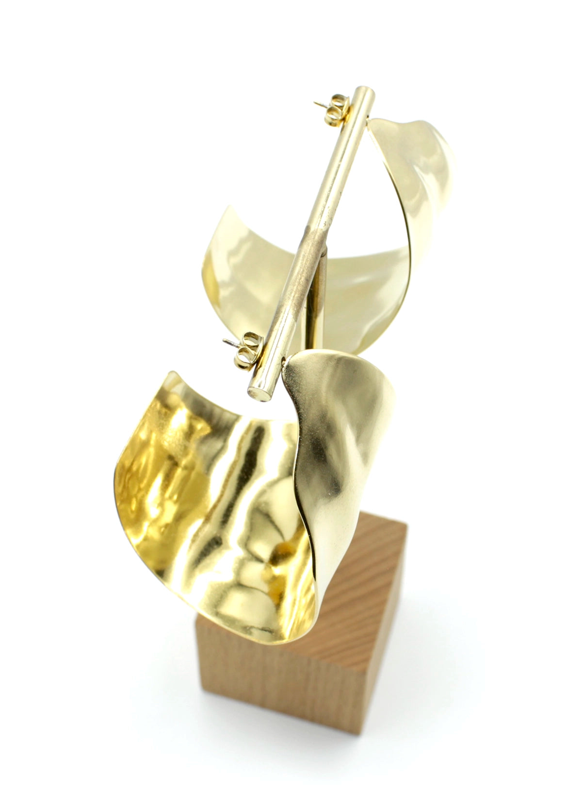 Pendientes Leaf acero inoxidable dorado colgados de un expositor, reflejan la luz con elegancia, curvos anchos dedicados para ser protagonistas de tu look. - DELACABRA