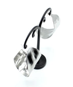 Pendientes Leaf acero inoxidable plateado en expositor de metal negro, diseño atemporal para gustos exquisitos. ligeros a pesar de su tamaño con cierre seguro y eficaz. - DELACABRA