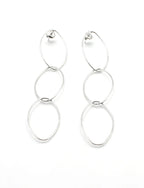 Pendientes largos de acero inoxidable plateado con diseño de tres aros enlazados sobre fondo blanco.