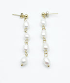 Pendientes Perle largos en acabado dorado con perlas blancas engarzadas, estilo minimalista y atemporal, hipoalergénicos y resistentes al agua – DELACABRA