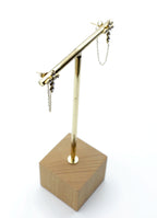 Pendientes Santo acero inoxidable dorado en un expositor dorado, diseño minimalista y elegante, ligero perfecto para usar todos los días. hipoalergénico acabado brillante. - DELACABRA
